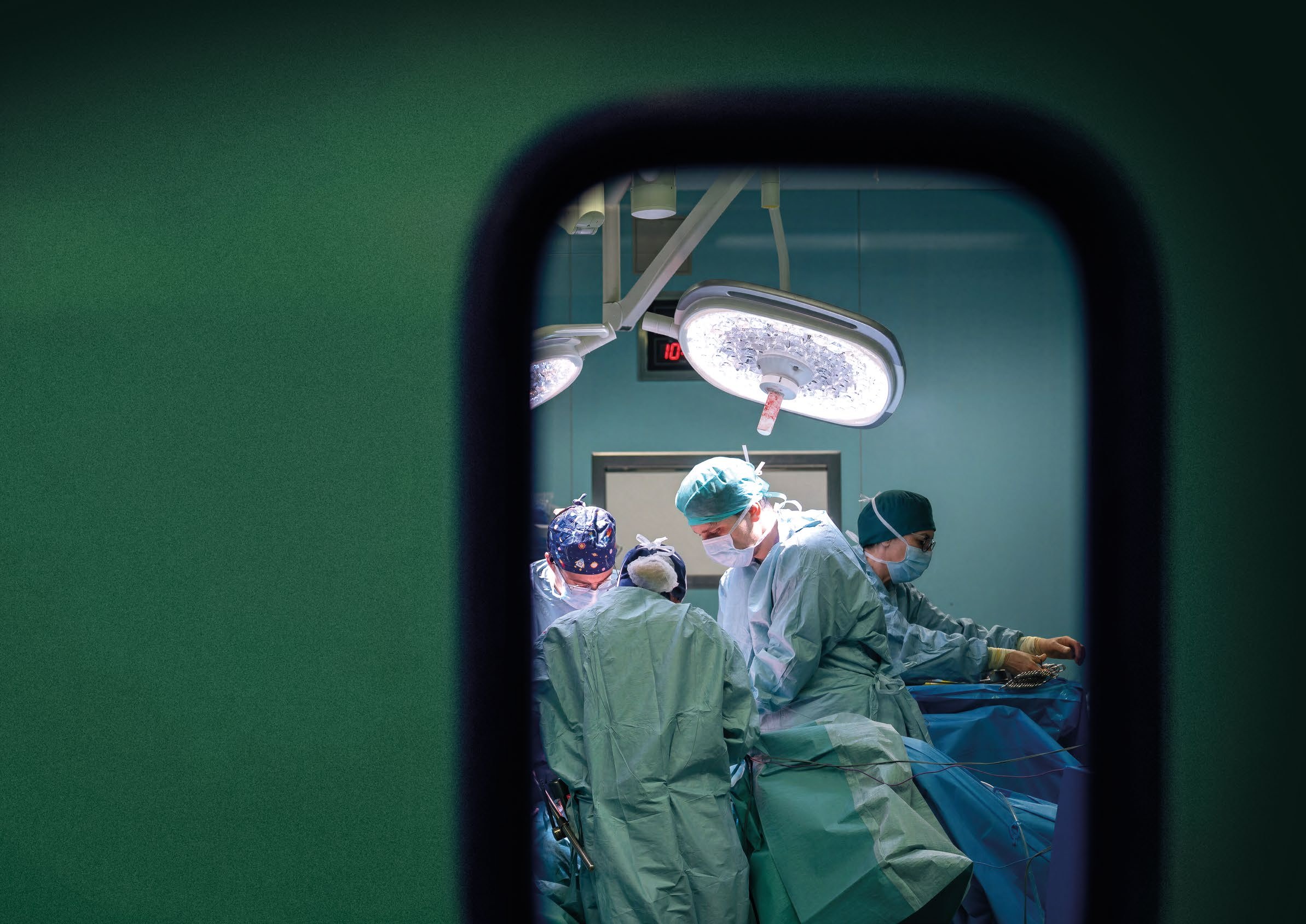 La sala operatoria di Candiolo vista attraverso l’oblò della porta, con l’équipe al lavoro